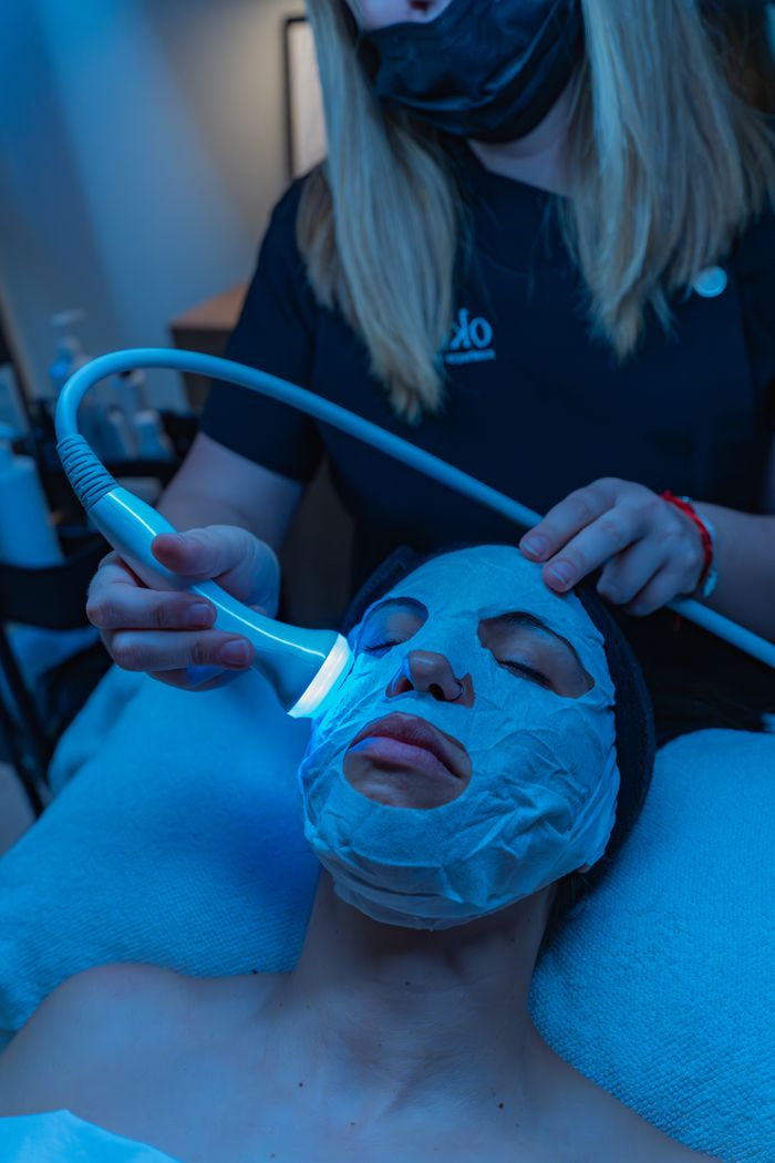 A relaxing spa facial treatment with a light therapy device for skincare rejuvenation.